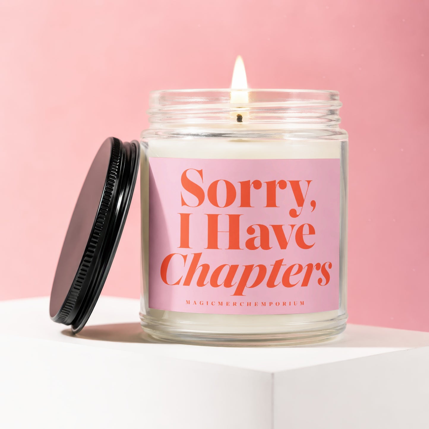 Candle in glass jar with burned wick and "Sorry, I Have Chapters" text on pink label.