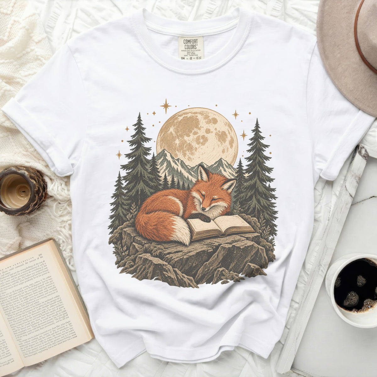 White t-shirt with a graphic of a fox reading a book under a full moon and trees.