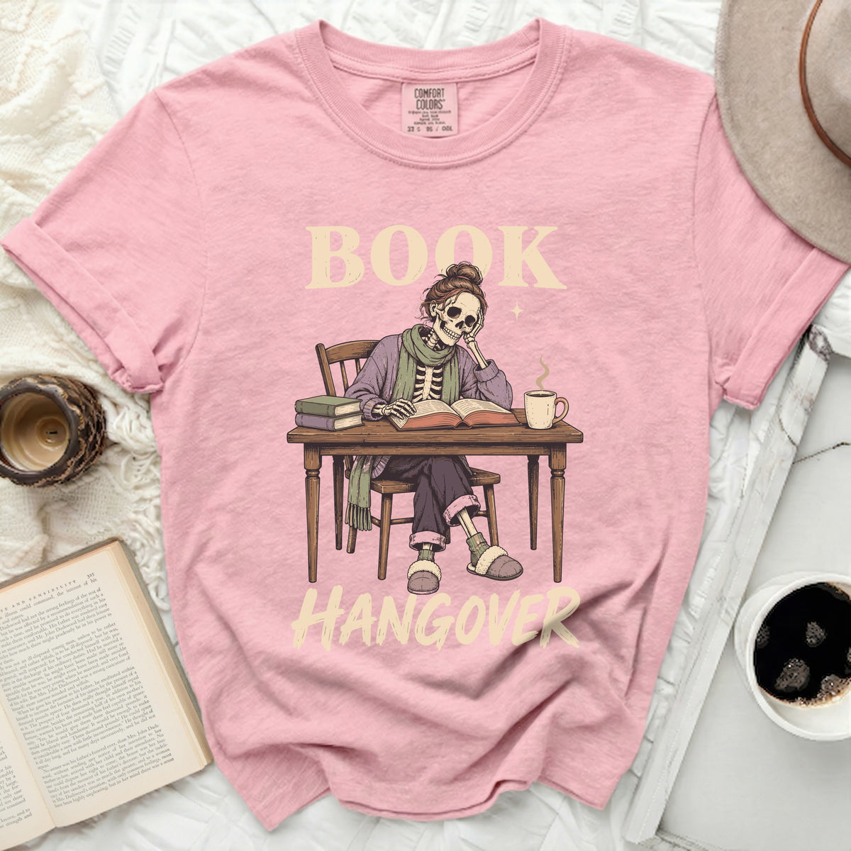 Pink t-shirt with skeleton reading a book and text "BOOK HANGOVER".