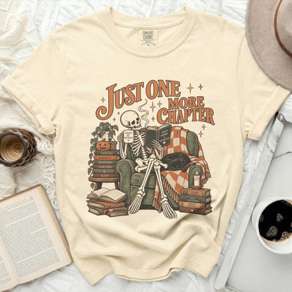 Skeleton reading with mug and book, "Just One More Chapter" text.