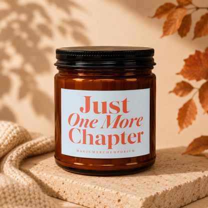 Amber jar candle with "Just One More Chapter" text, on a textured stone.