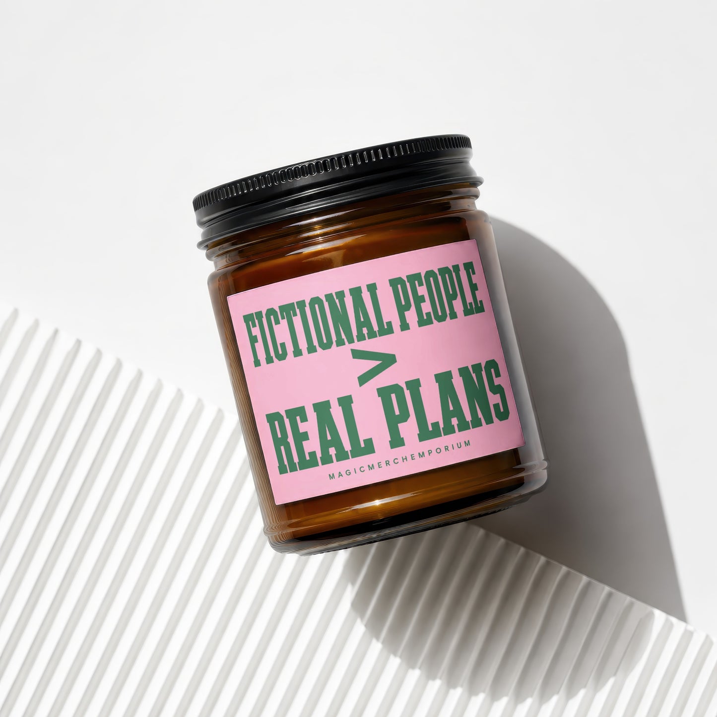 Amber jar candle with pink label reading "FICTIONAL PEOPLE > REAL PLANS"