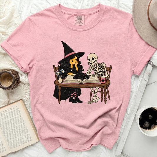 Witch and skeleton reading a book with a black cat.