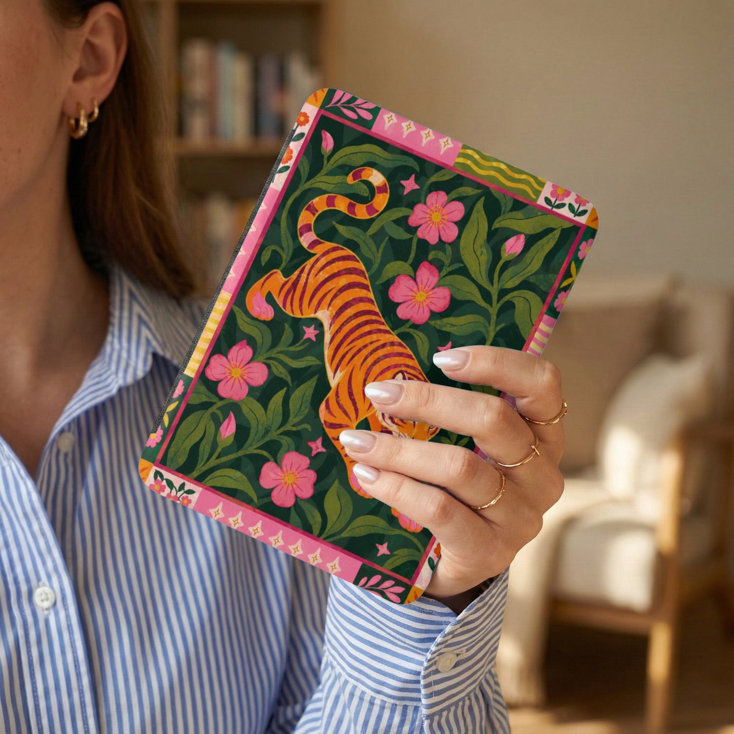 Case with tiger and floral pattern held by person wearing striped shirt.