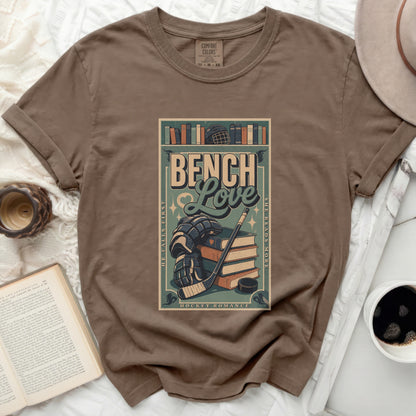 Brown t-shirt with a distressed graphic of books, hockey puck, stick, and skates.