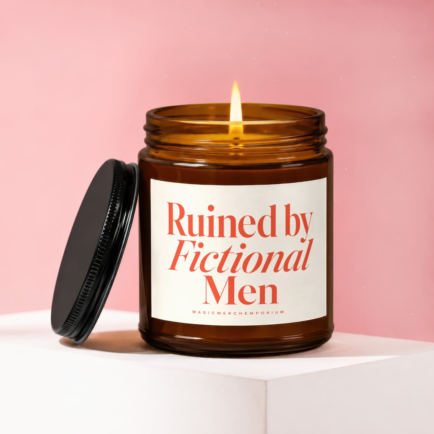 Amber candle with lit wick, lid off, label reads "Ruined by Fictional Men".