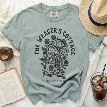 Pale blue t-shirt with "The Weaver's Cottage" and spinning wheel graphic.