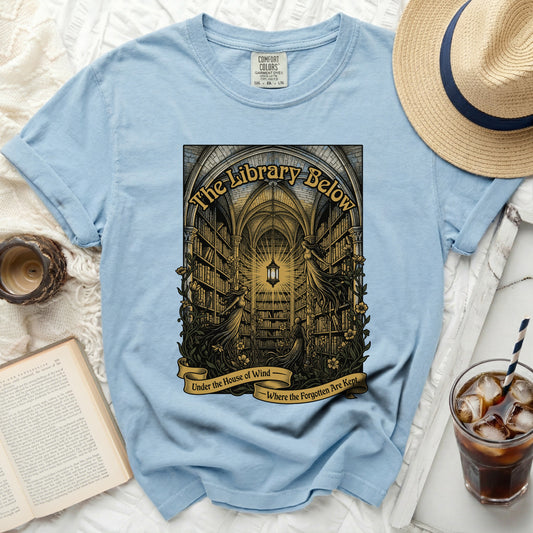 Light blue t-shirt with a graphic of a library, two female figures, and text.