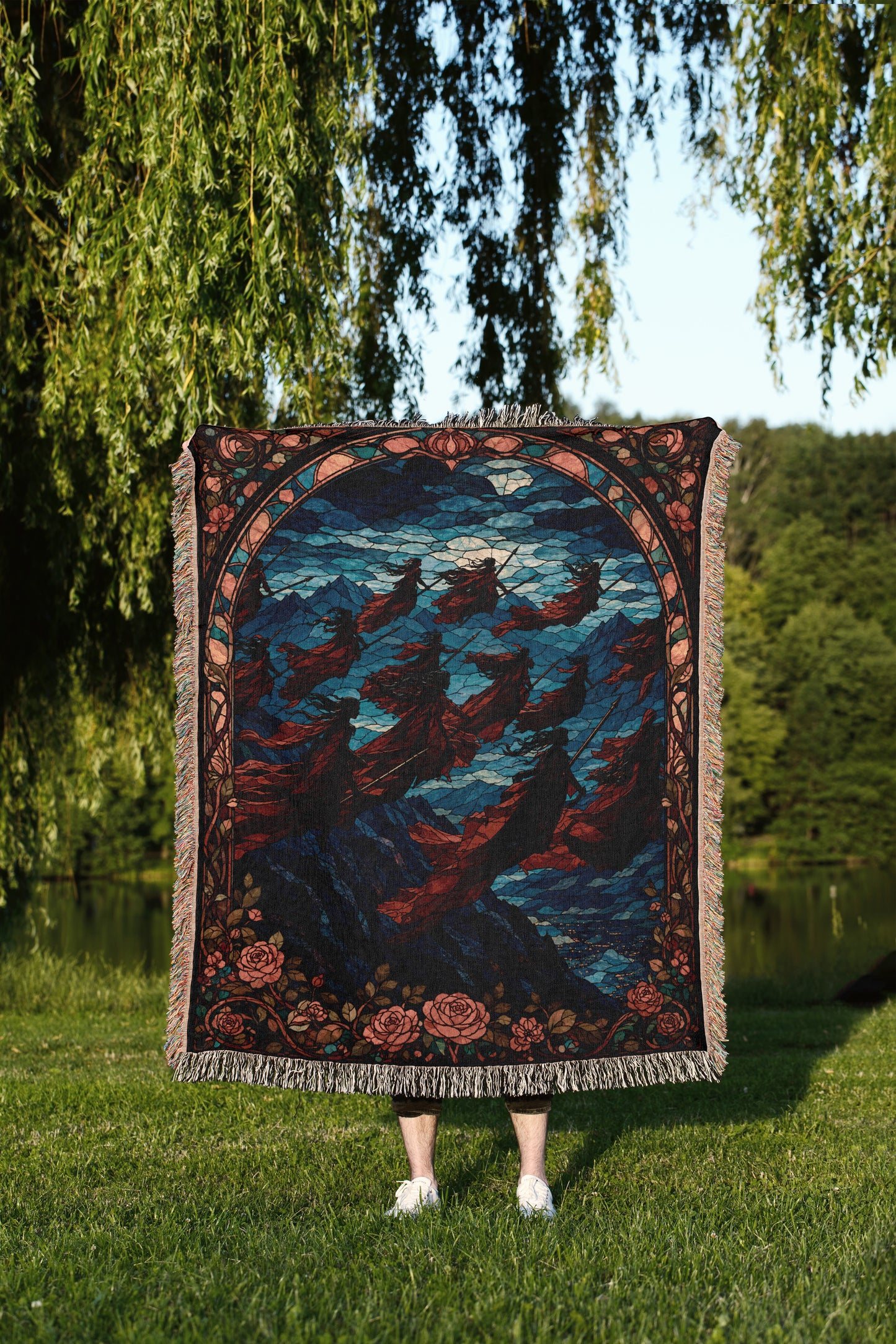 A person stands in a grassy field, holding a large, colorful rug with a floral pattern.