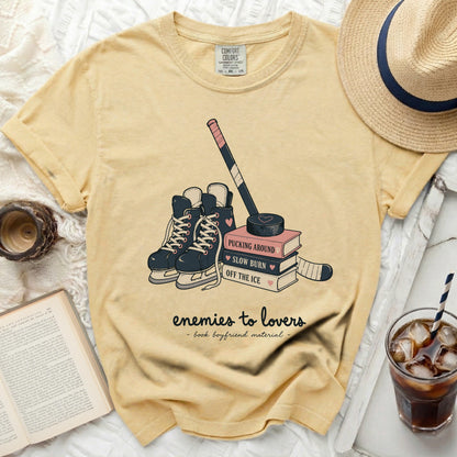 Yellow t-shirt with hockey skates, puck, stick, and books titled "Pucking Around."