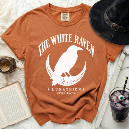 Orange t-shirt with "The White Raven Lunathion Open Late" graphic and a raven on a crescent moon.