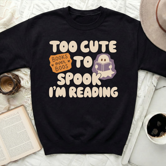 Black sweatshirt with "Too Cute To Spook I'm Reading" text and ghost.