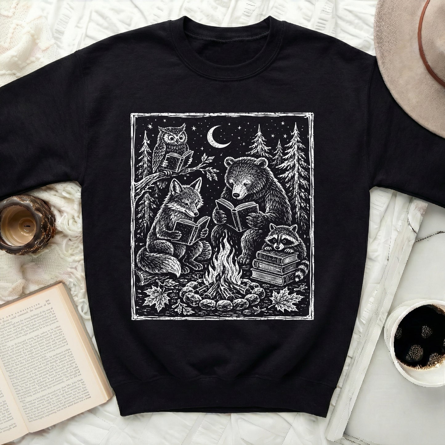 Black sweatshirt with linocut print of woodland animals reading by a campfire.