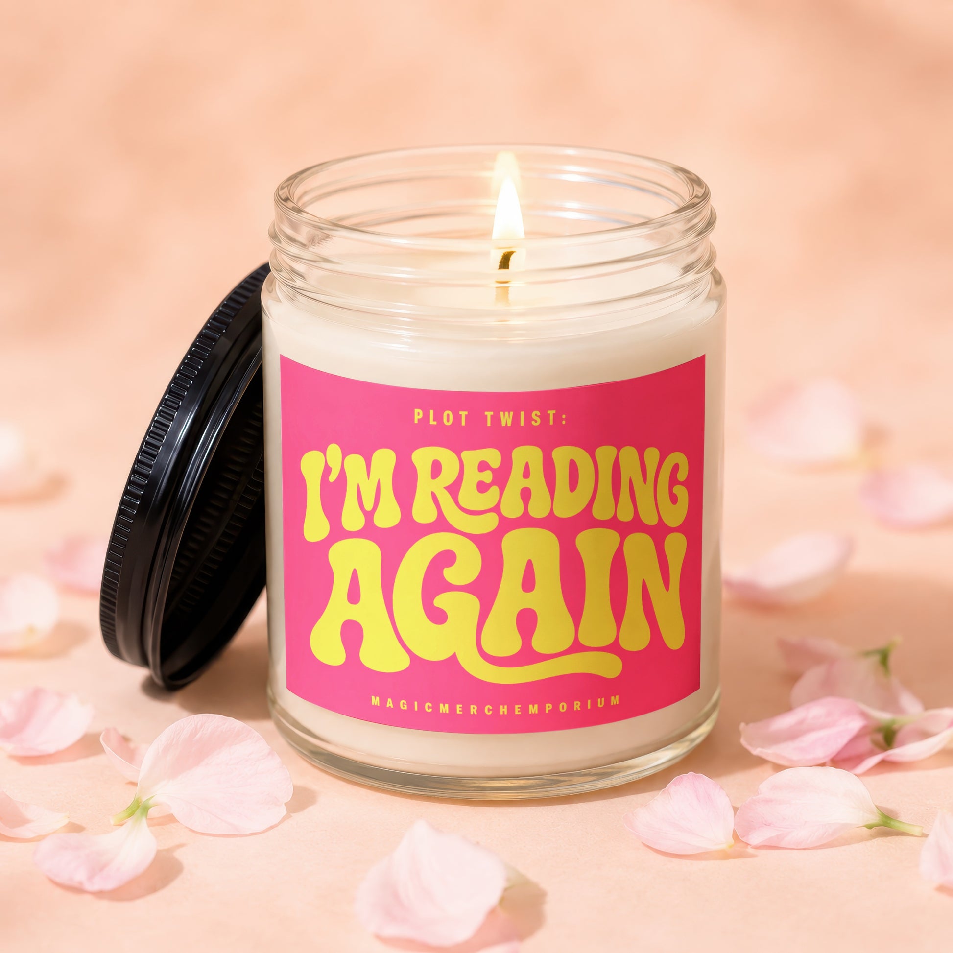 Lit candle in glass jar with pink label reading "PLOT TWIST: I'M READING AGAIN".