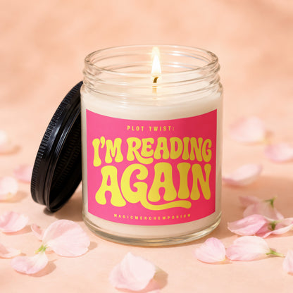 Lit candle in glass jar with pink label reading "PLOT TWIST: I'M READING AGAIN".