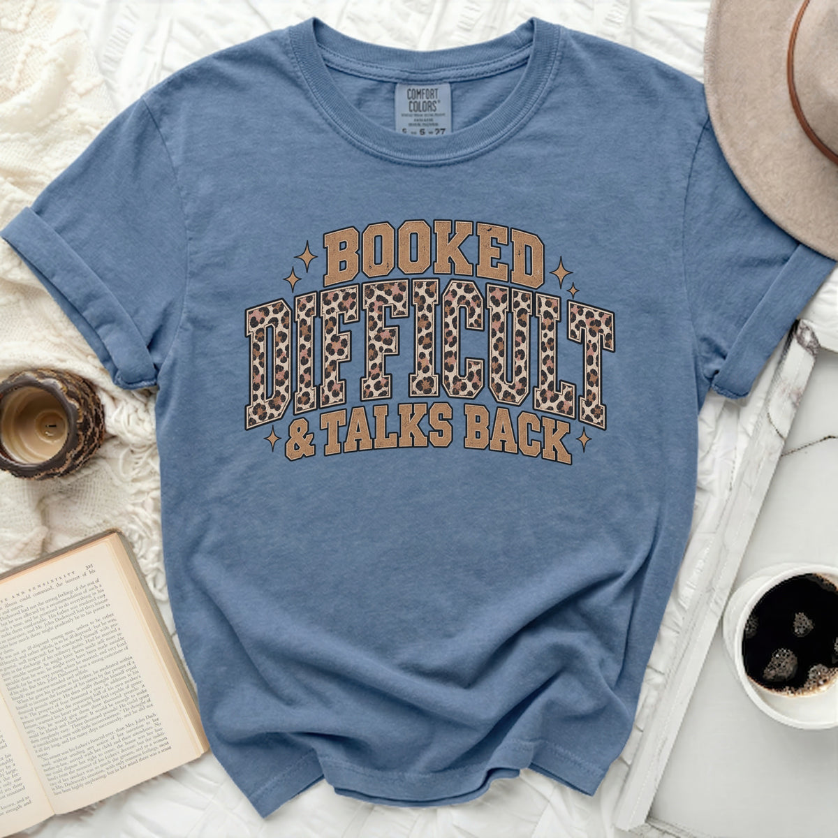Blue t-shirt with "Booked Difficult & Talks Back" text and leopard print accents.