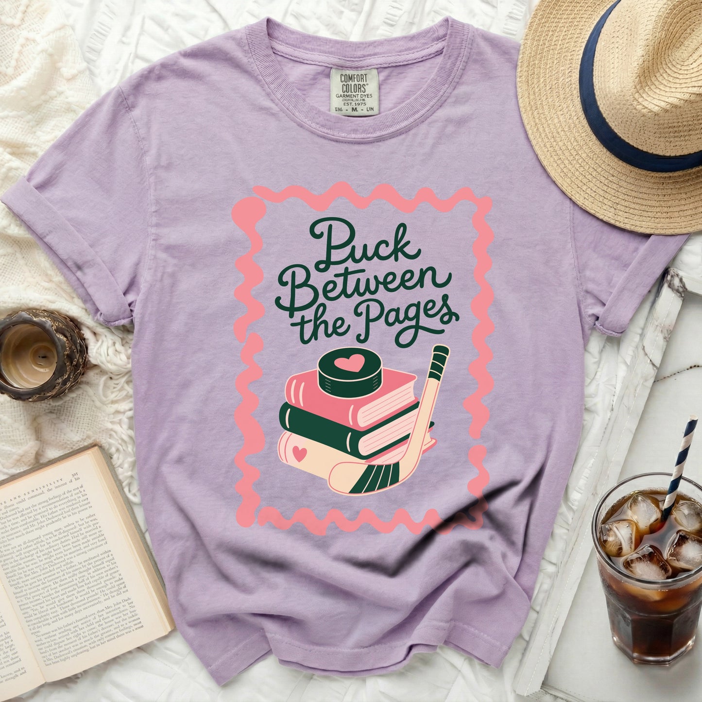 Purple t-shirt with "Puck Between the Pages" and hockey graphic.