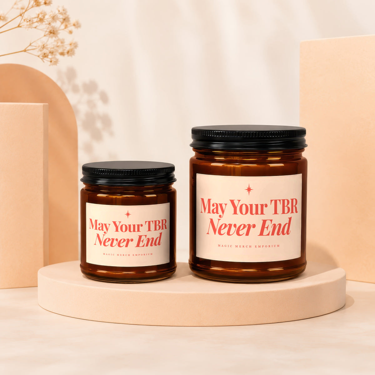 Two amber glass candles with black lids display "May Your TBR Never End" in red text.