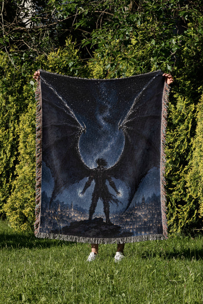 A person is holding up a large blanket with a dragon design on it, standing in a grassy area with trees in the background.
