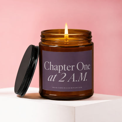 Amber jar candle with lit wick, black lid, and "Chapter One at 2 A.M." label.