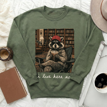 Green crewneck sweatshirt with a raccoon in sunglasses and a hat drinking from a cup.