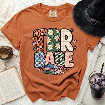 TBR Babe graphic tee with books and decorative elements.