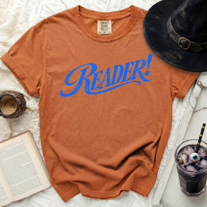 Orange t-shirt with "READER!" in blue script, next to a witch hat.