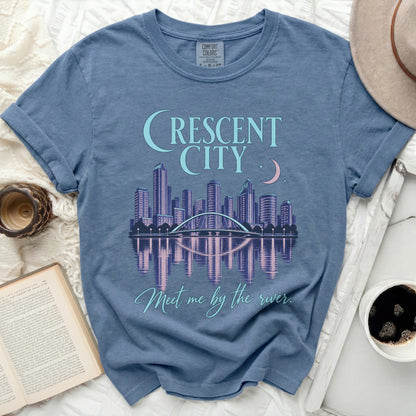 Blue t-shirt with "CRESCENT CITY" text, city skyline, bridge, and "Meet me by the river."