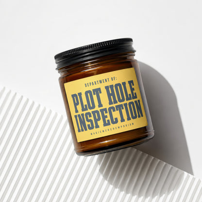 Amber jar candle labeled "Department of: Plot Hole Inspection" and "Magic Merch Emporium"