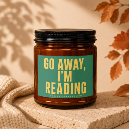 Amber glass candle with green label reading "GO AWAY, I'M READING".
