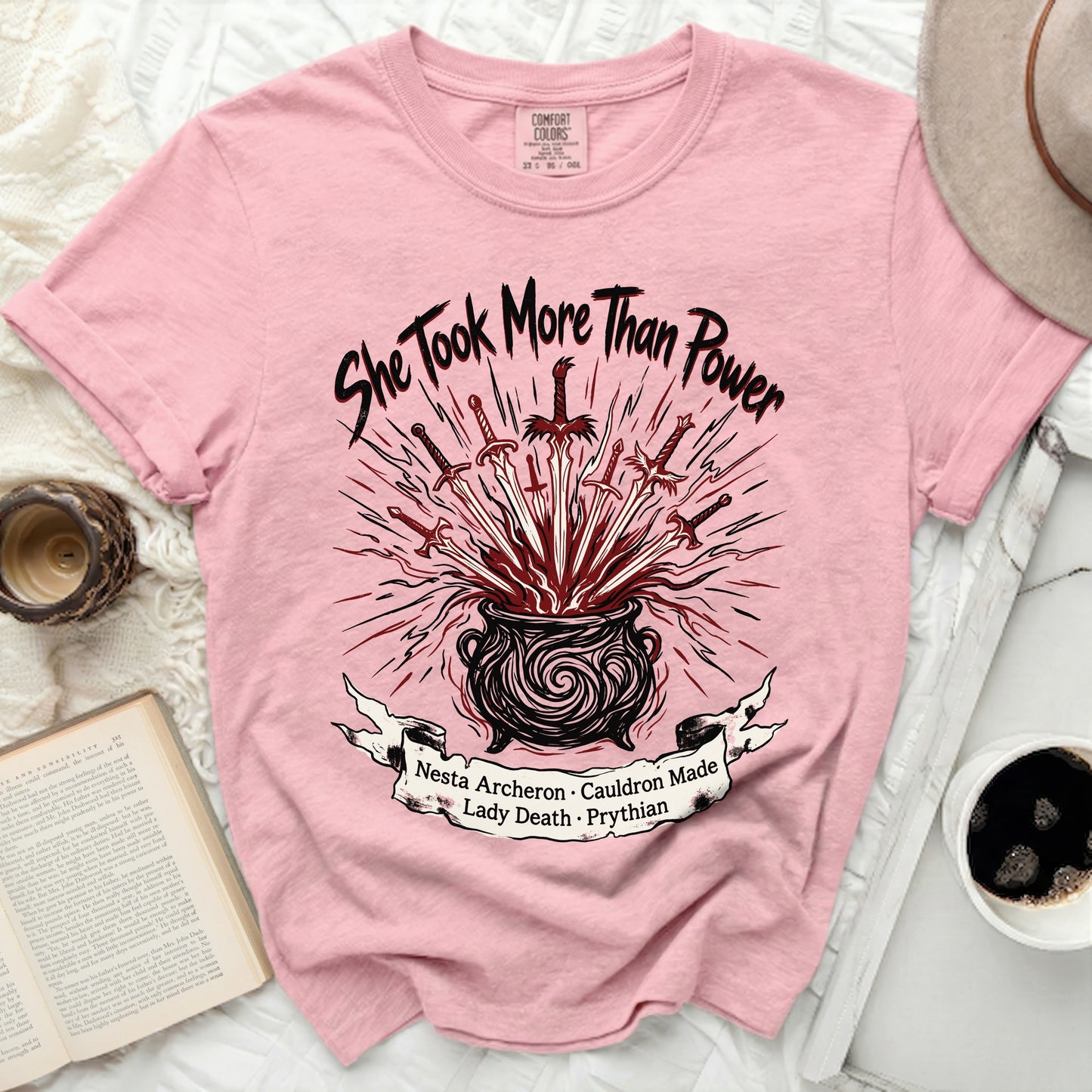 Pink t-shirt with "She Took More Than Power" and swords in cauldron design.