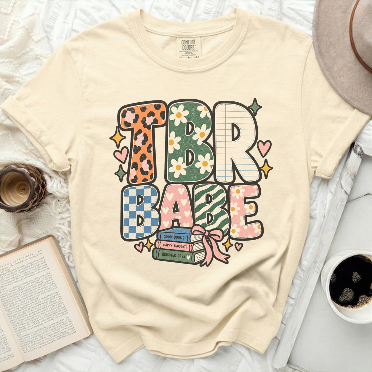 Cream t-shirt with "TBR BABE" text in colorful, patterned letters.
