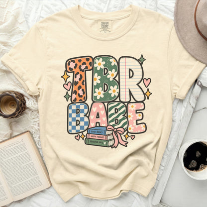 Cream t-shirt with "TBR BABE" text in colorful, patterned letters.