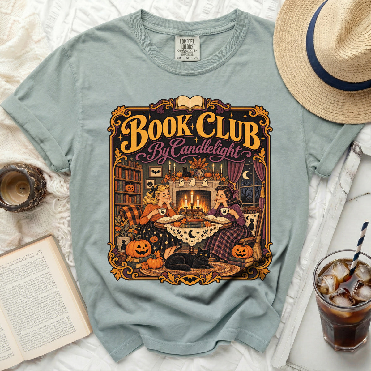 "Book Club by Candlelight" graphic on a light blue t-shirt with a witchy, cozy scene.