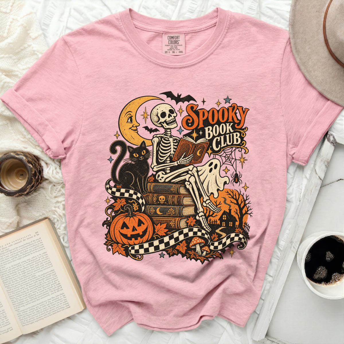Skeleton reading book with "Spooky Book Club" text, black cat, pumpkin, and moon.