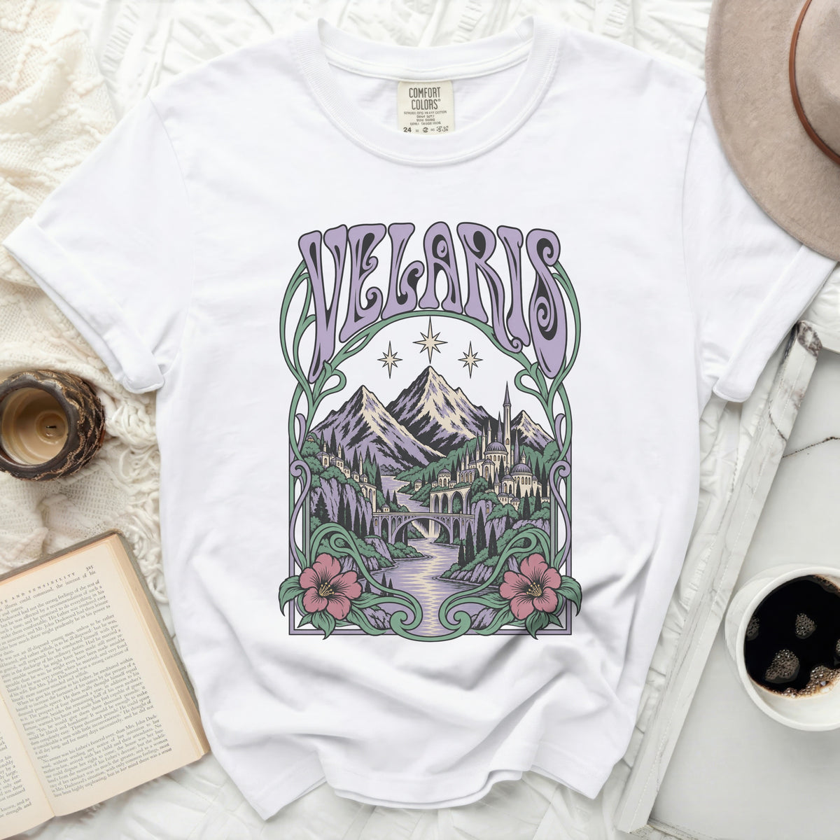 White t-shirt with a purple and green graphic of a fantasy city and mountains.