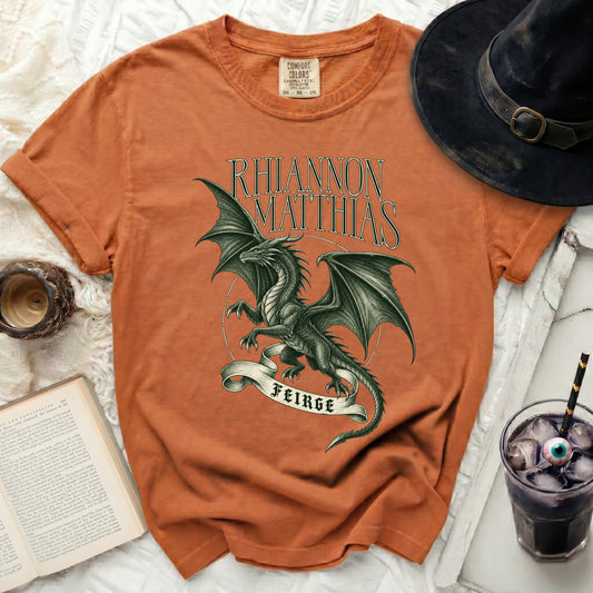 Orange t-shirt with a black dragon design and text "RHIANNON MATTHIAS FEIRGE".