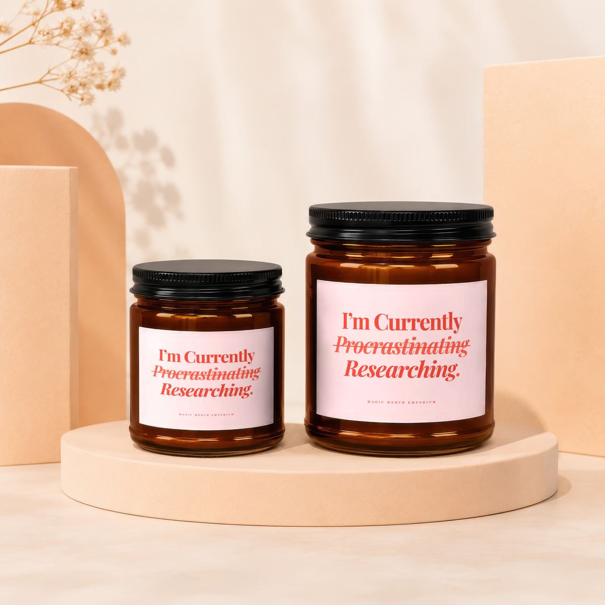 Two amber glass candles with pink labels reading "I'm Currently Procrastinating Researching."
