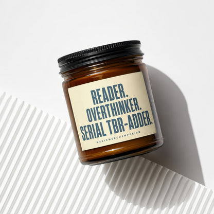 Amber jar candle with a beige label that reads "READER. OVERTHINKER. SERIAL TBR-ADDER."