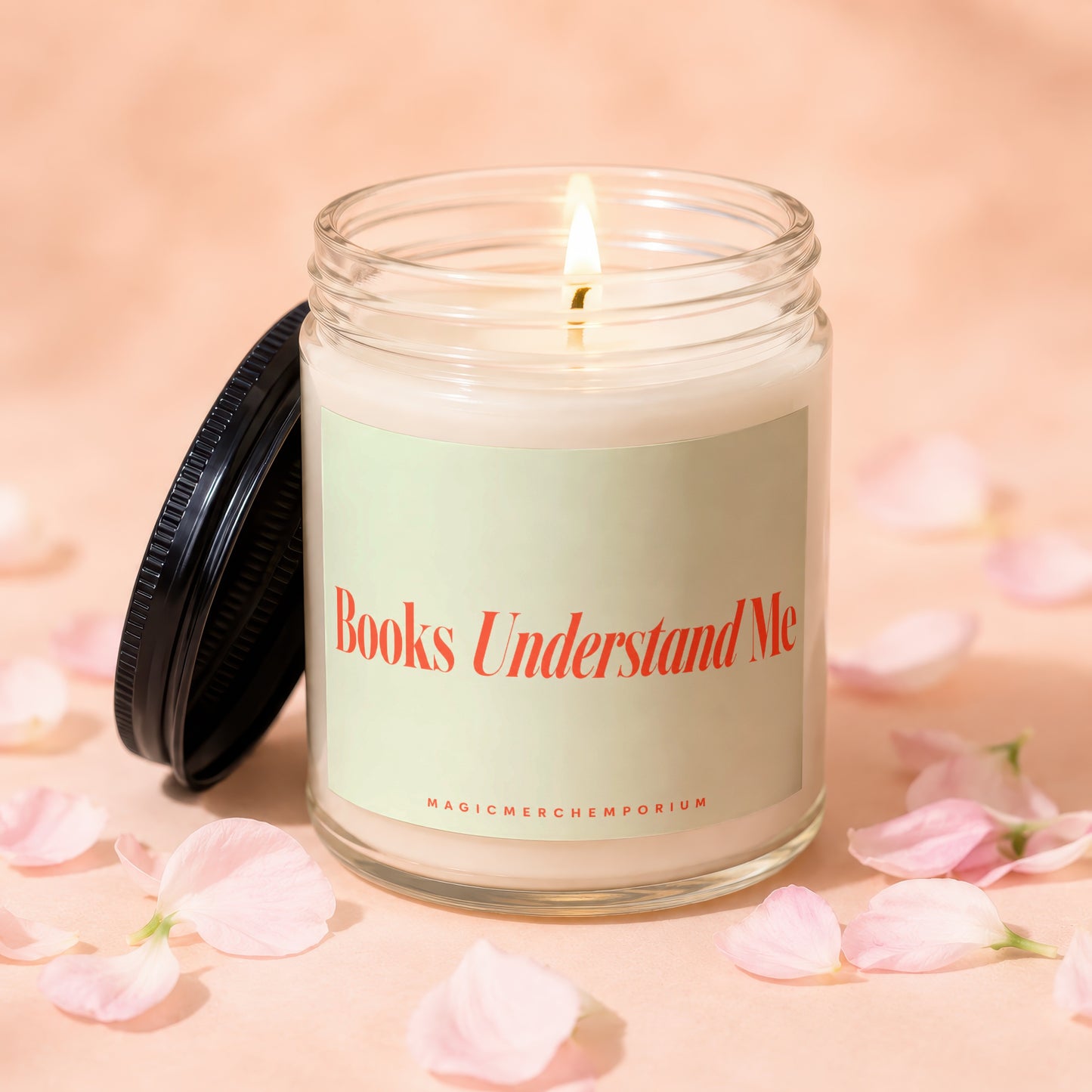Lit candle with "Books Understand Me" on label, surrounded by pink petals.