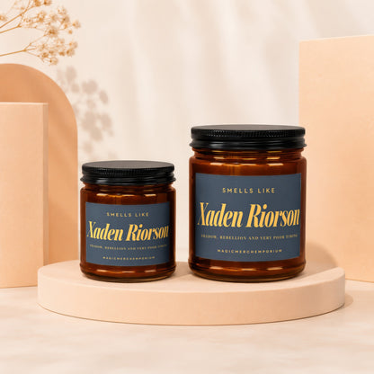 Two brown glass candles labeled "Xaden Riorson" with gold text.