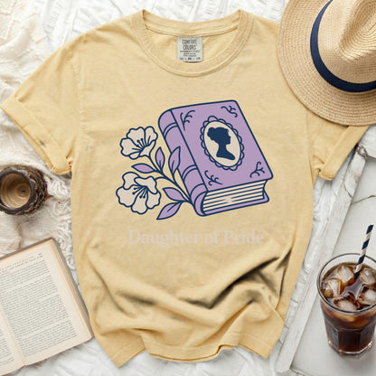 Yellow t-shirt with purple book, flowers, and silhouette for "Daughter of Pride".