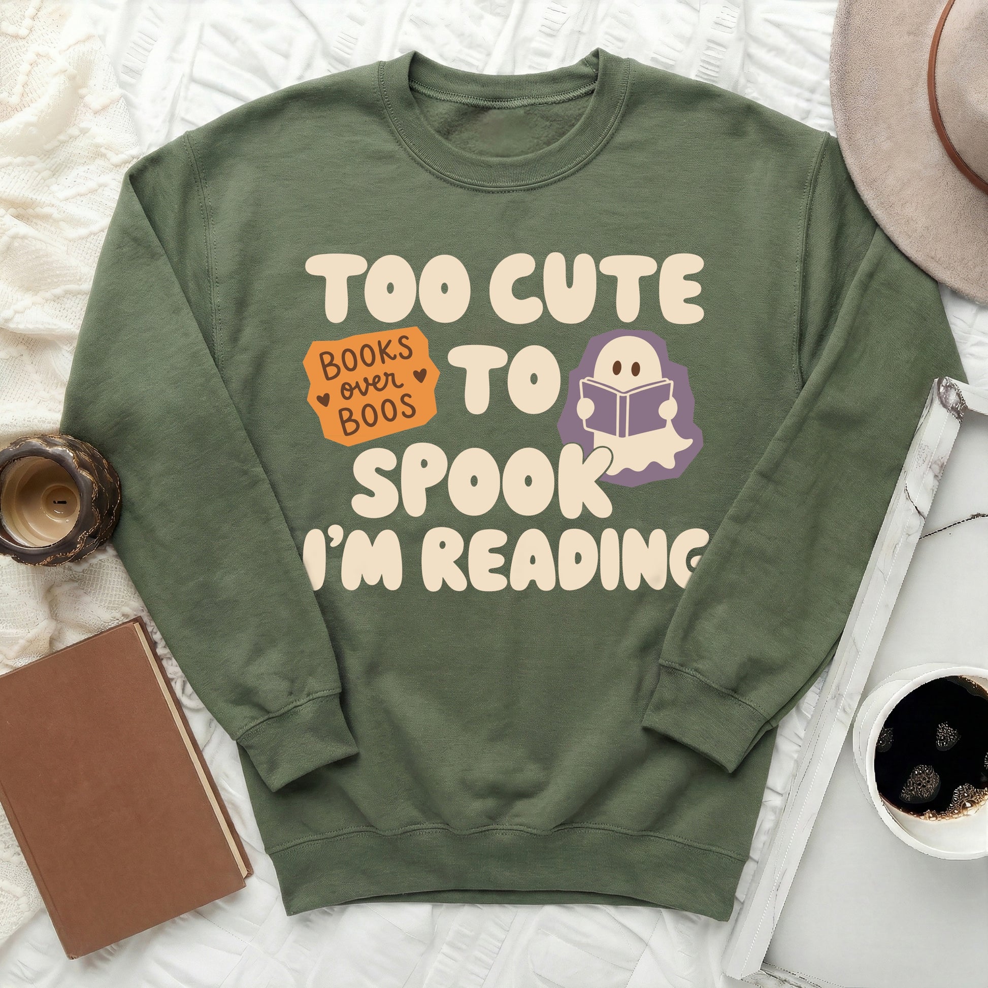 Green sweatshirt with text "Too Cute to Spook, I'm Reading" and a ghost.