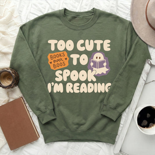 Green sweatshirt with text "Too Cute to Spook, I'm Reading" and a ghost.