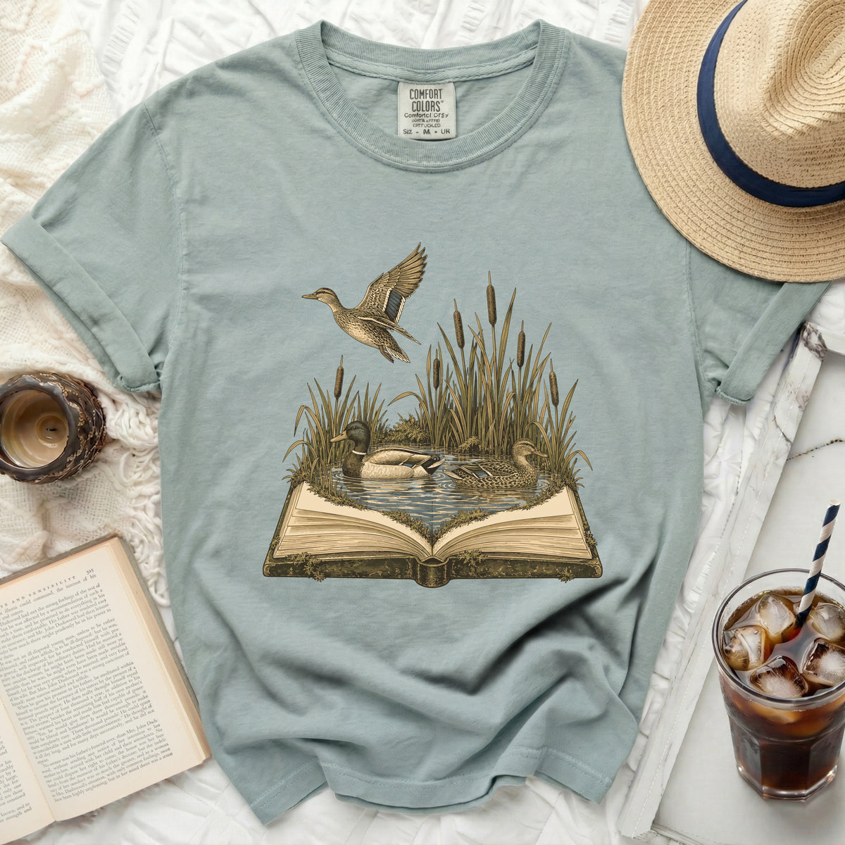 T-shirt with a graphic of ducks in reeds emerging from an open book.