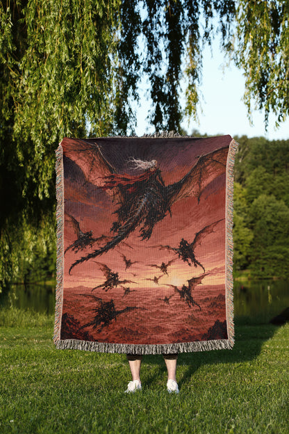A person is standing in a grassy area, holding a large tapestry or blanket that features a dragon design.