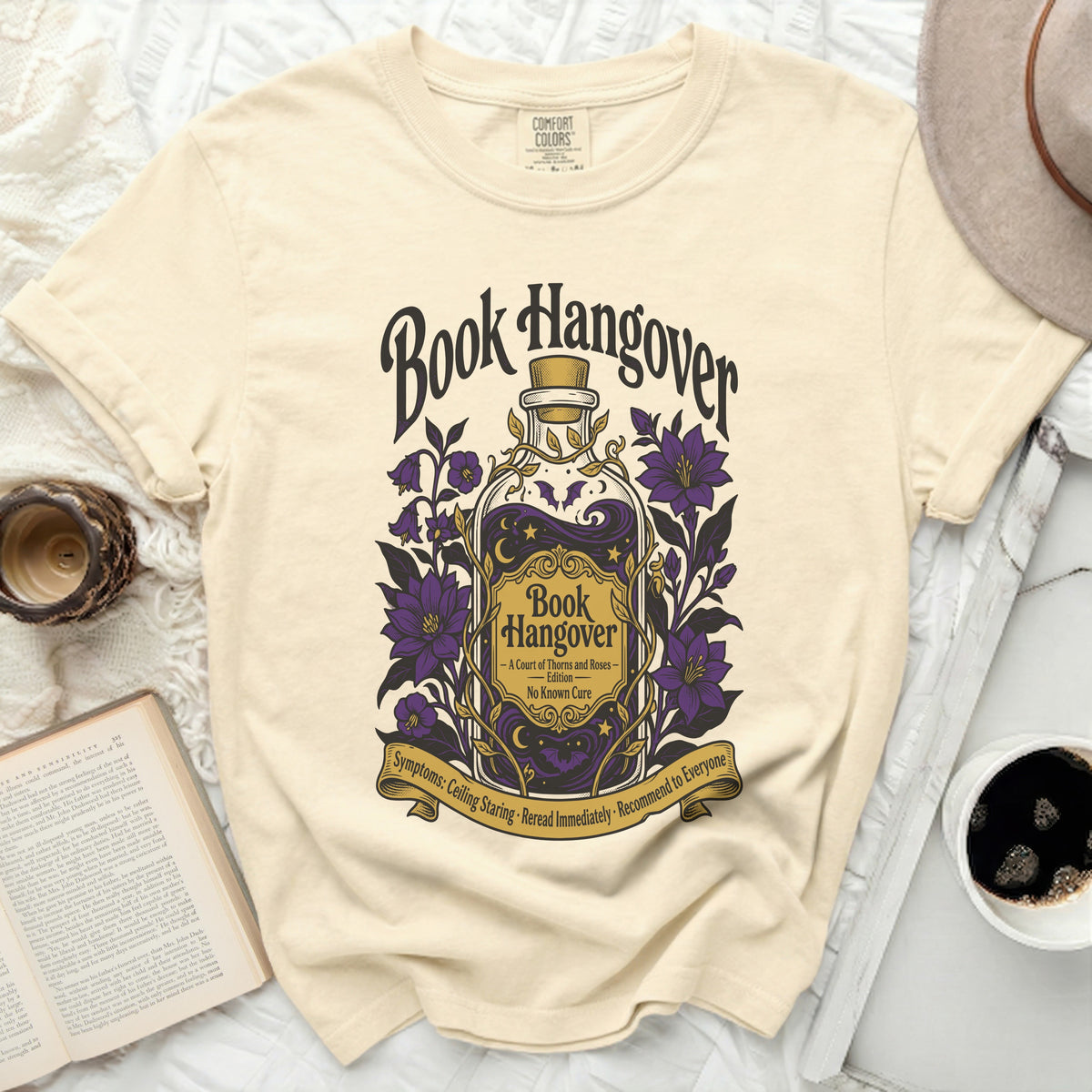 Book Hangover t-shirt with a potion bottle, purple flowers, and text.