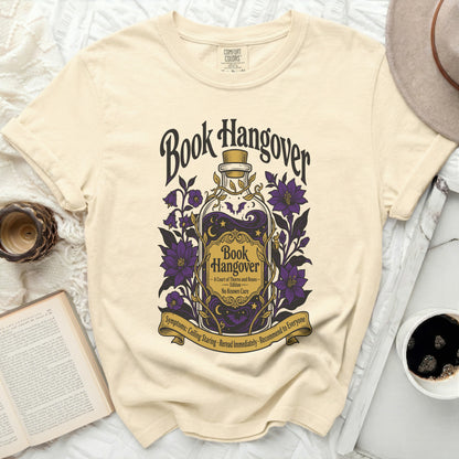Book Hangover t-shirt with a potion bottle, purple flowers, and text.