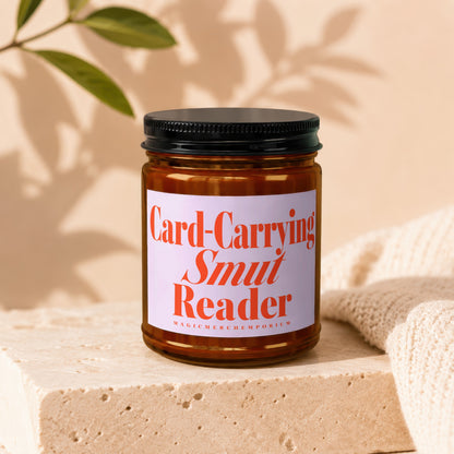 Amber jar candle with black lid reads "Card-Carrying Smut Reader".