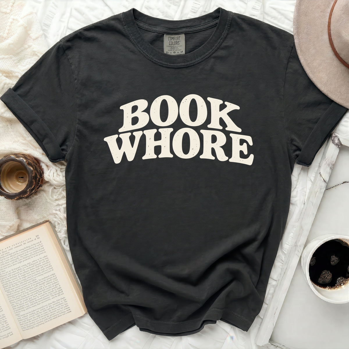 Dark grey t-shirt with "BOOK WHORE" text in cream wavy font.